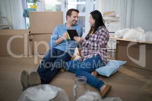 Couple using digital tablet at their new home