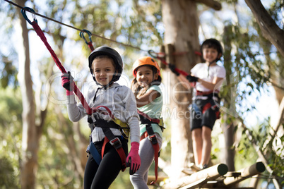 Portrait of happy kids crossing zip line