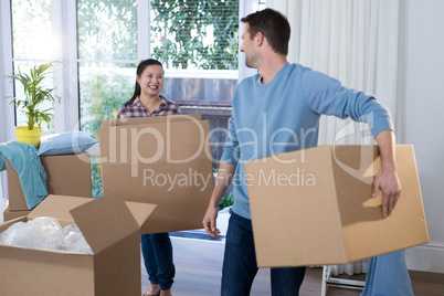 Couple carrying big cardboard box at new home