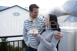 Pregnant woman and her husband holding baby socks in balcony