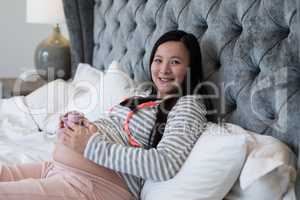 Pregnant woman looking at holding socks in bedroom