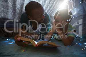 Father and son reading book in bedroom