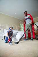 Father and daughter in superhero costume and cleaning a floor