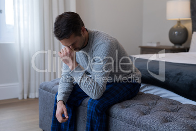 Tensed man sitting on bed