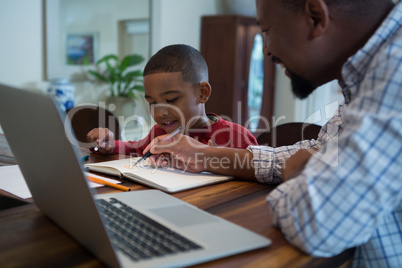 Father helping his son with homework in living room