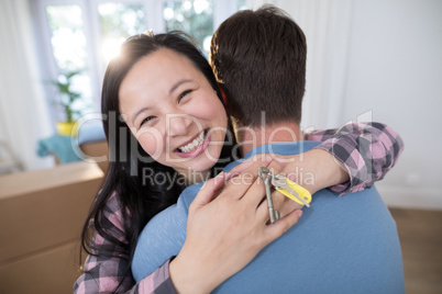 Couple embracing each other while holding keys of new home