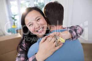 Couple embracing each other while holding keys of new home