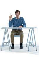 Male executive pointing upwards while sitting at desk