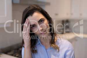 Woman suffering from headache in kitchen