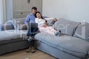 Couple using laptop on sofa