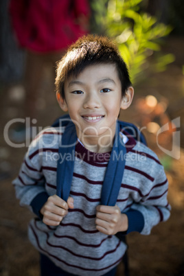 Cute boy standing with school bag