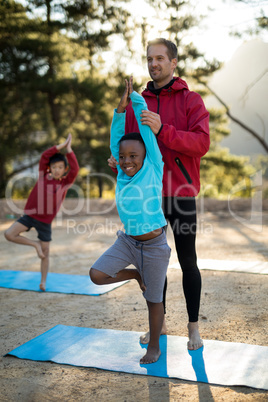 Coach assisting kids in practicing yoga