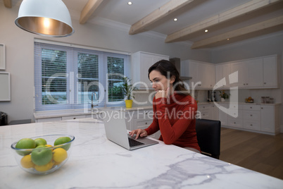 Woman using laptop in kitchen