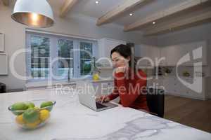 Woman using laptop in kitchen