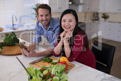 Couple leaning on the kitchen worktop with vegetables in front