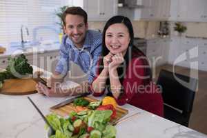 Couple leaning on the kitchen worktop with vegetables in front