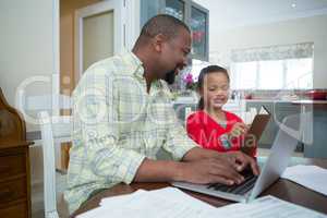 Daughter showing diary to father in kitchen