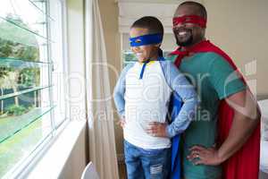 Father and son in superhero costume looking through window