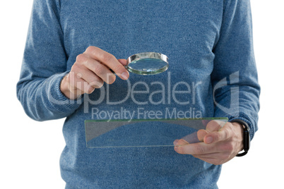 Male executive holding magnifying glass and digital tablet