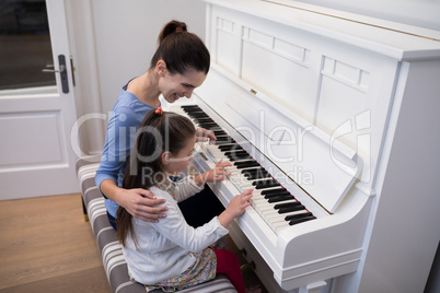 Mother assisting daughter in playing piano