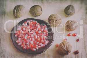 Pomegranate fruits on the plate and walnuts.