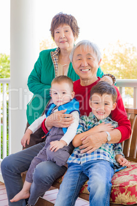Senior Adult Chinese Couple Sitting With Their Mixed Race Grandc