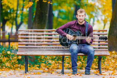 Young man standing in park with guitar