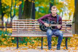 Young man standing in park with guitar