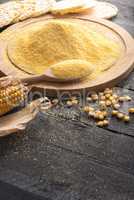 Corn flour on wooden board and grains