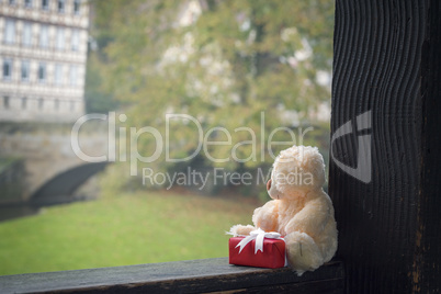 Teddy bear and gift on a wooden beam