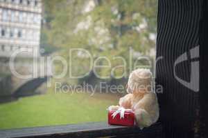 Teddy bear and gift on a wooden beam