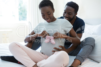 Couple holding baby socks in bedroom
