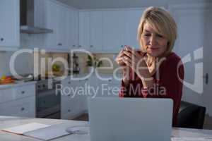Woman looking at laptop while having lemon tea