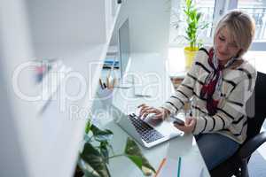 Woman using mobile phone and laptop at table
