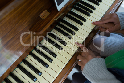 Mother assisting daughter in playing piano at home