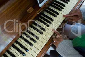 Mother assisting daughter in playing piano at home