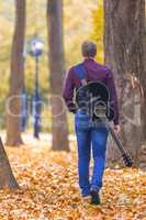 Young man with guitar walking in park