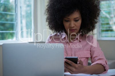 Woman using mobile phone while working at desk