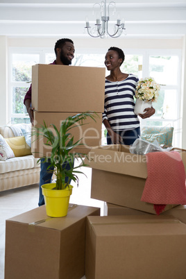 Couple carrying big cardboard box and vase at new home