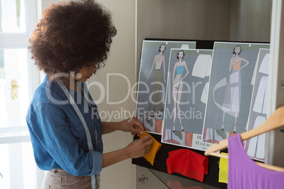 Female fashion designer attaching fabric on bulletin board