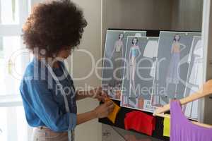 Female fashion designer attaching fabric on bulletin board