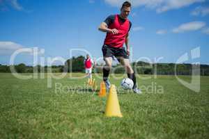 Soccer player dribbling through cones