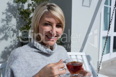 Portrait of happy woman having lemon tea in porch