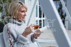 Thoughtful woman having lemon tea in porch