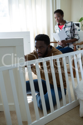 Man making cot with pregnant woman in bedroom