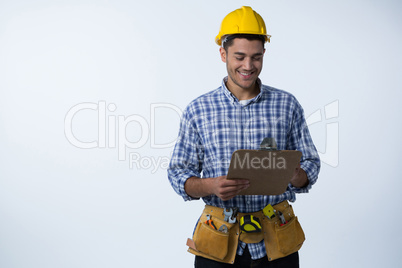 Male architect looking at clipboard against white background