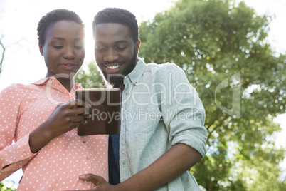 Couple using digital tablet in park