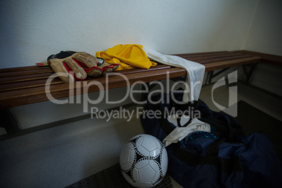 Gloves with football jersey, soccer ball and travel bag on bench