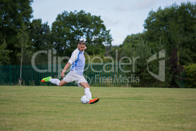 Football player kicking the soccer on the football ground