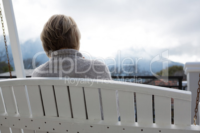 Rear view of thoughtful woman relaxing in porch